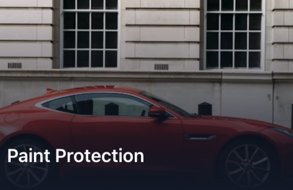 Red sports car parked in front of a building with large windows.